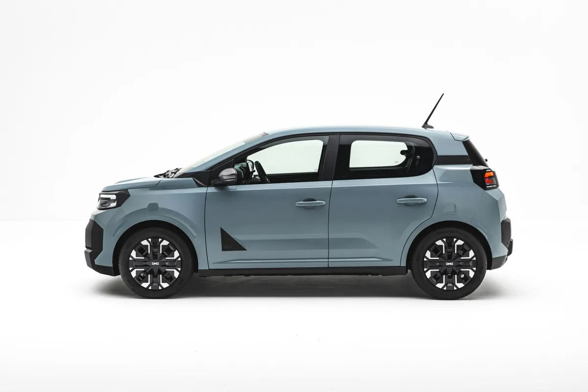 Hellblauer Dacia Spring im Seitenprofil vor weißem Studiohintergrund.