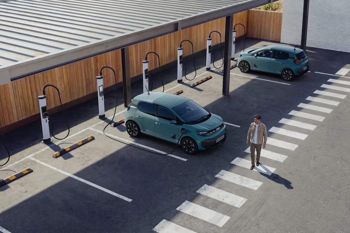Zwei hellblaue Dacia Spring von oben an einer öffentlichen Ladestation mit mehreren Ladesäulen.