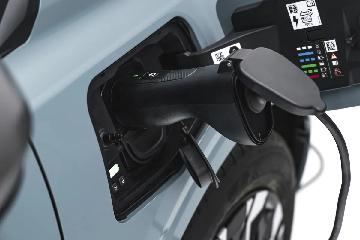 Nahaufnahme des geöffneten Ladeanschlusses eines Dacia Spring mit eingestecktem schwarzem Stecker.