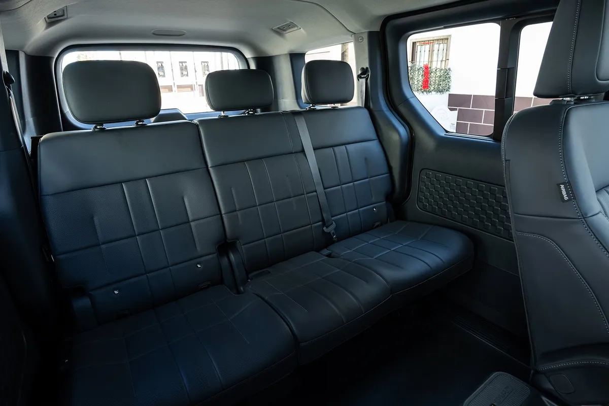 Dreisitzige Rückbank im Kia PV5 Passenger mit dunklen Bezügen und großen Seitenfenstern.