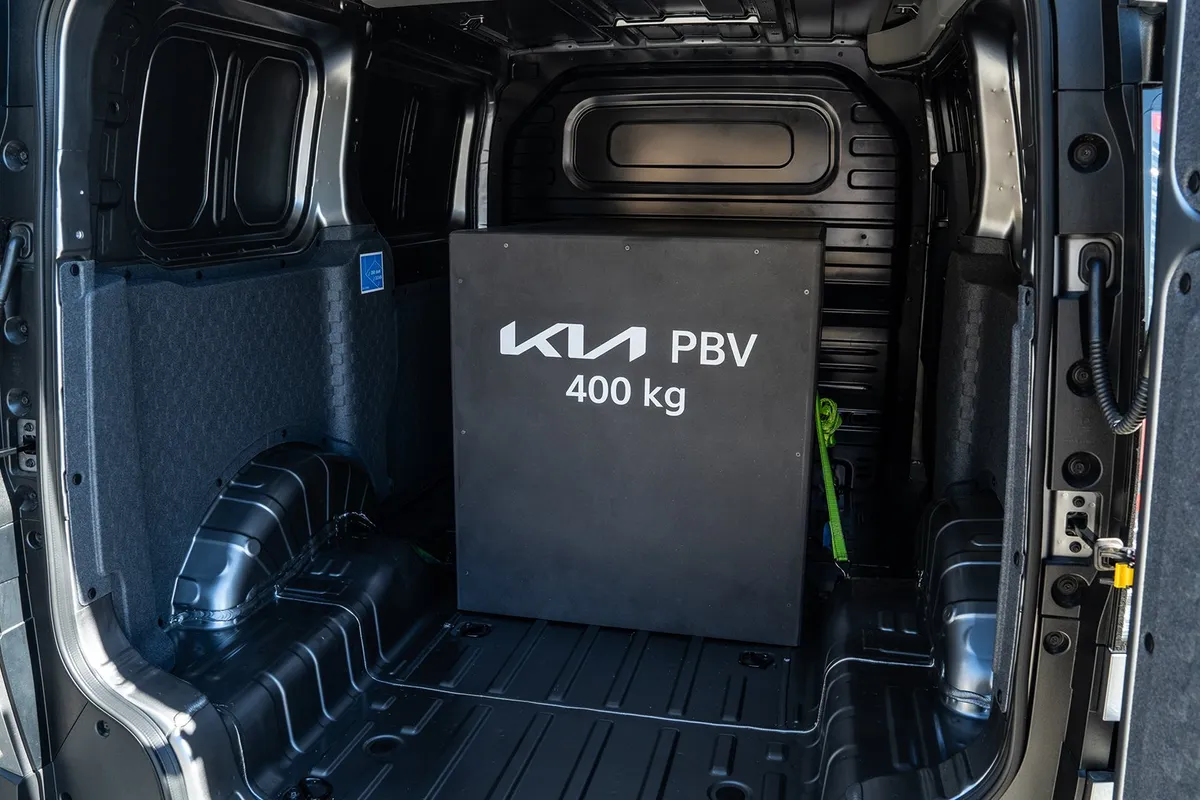 Laderaum des Kia PV5 Cargo von hinten mit einem schwarzen Gewicht mit der Aufschrift KIA PBV 400 kg.