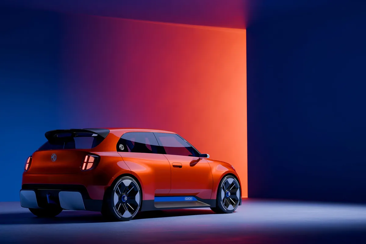 Oranges MG GO! Concept von schräg hinten mit schwarzem Dachspoiler vor blau-orange beleuchtetem Studiohintergrund.