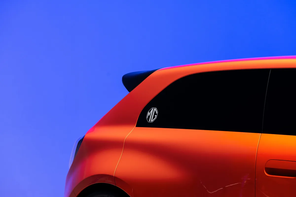 Nahaufnahme des hinteren Seitenfensters mit MG-Logo und schwarzem Dachspoiler des orangen MG GO! Concept.