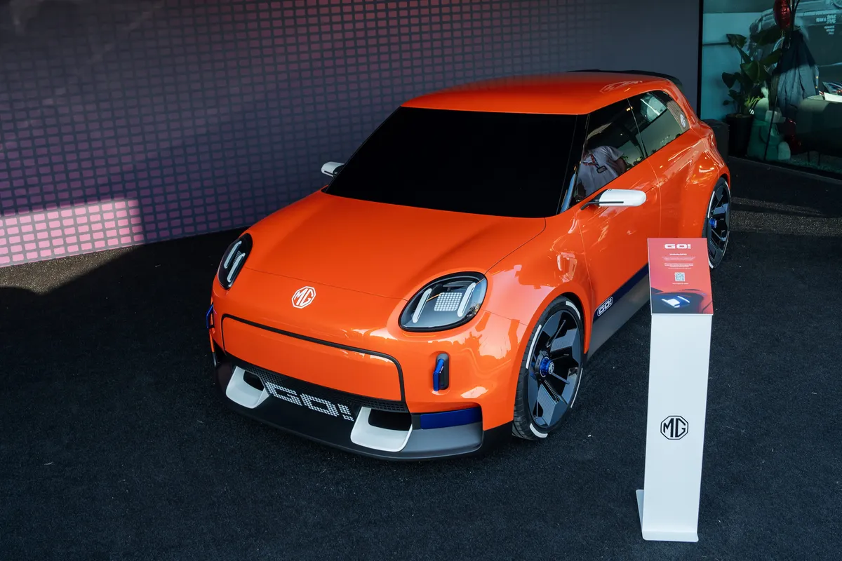 Oranges MG GO! Concept von schräg vorne und leicht von oben auf einem dunklen Messestand.