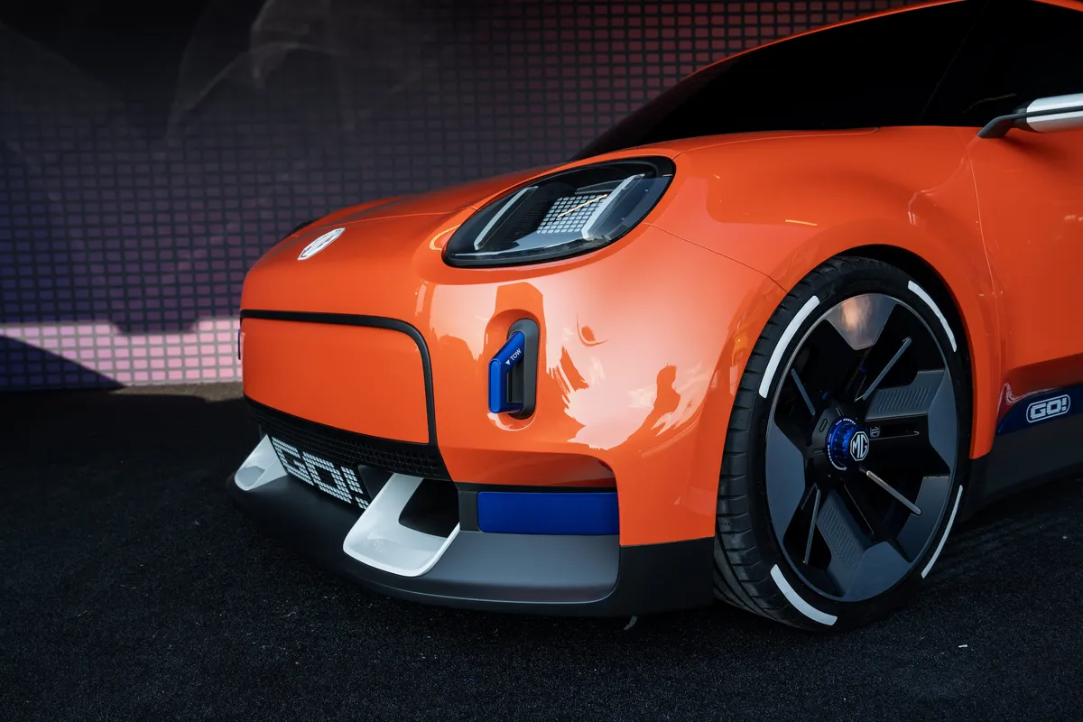 Tiefe Nahaufnahme von Scheinwerfer, Stoßfänger und Vorderrad des orangen MG GO! Concept.