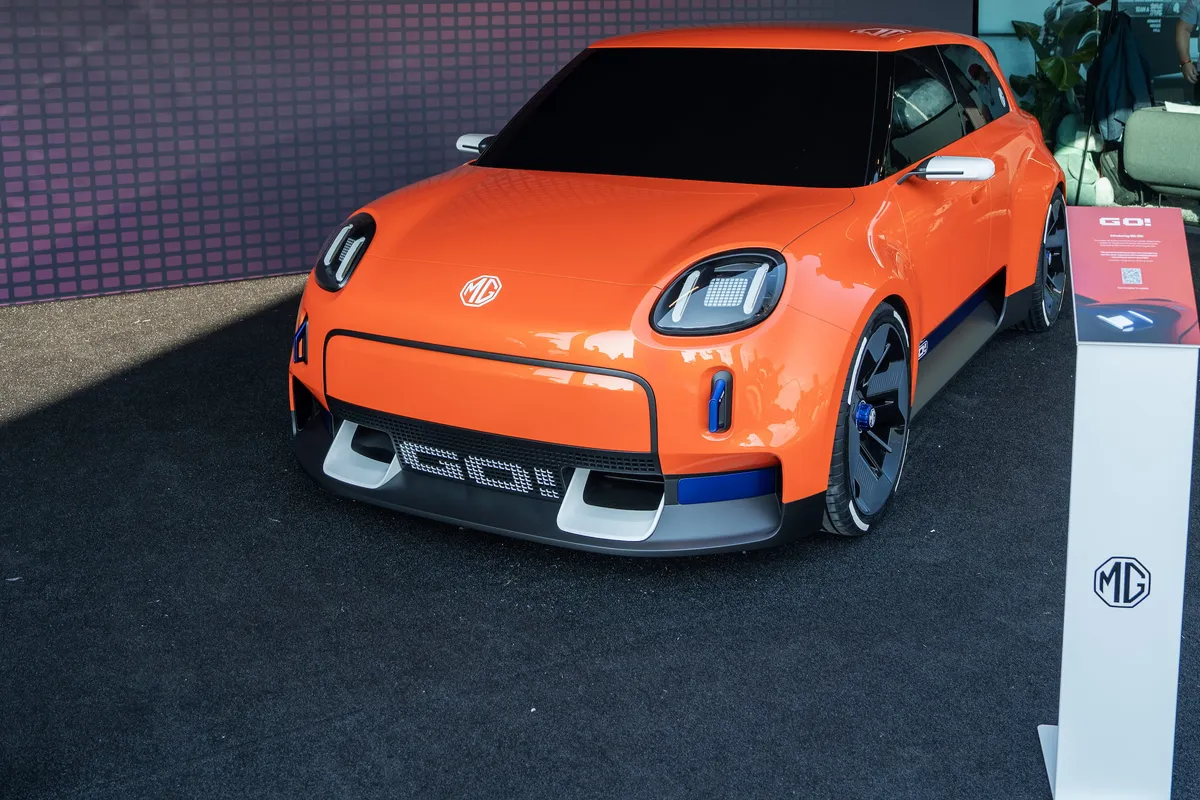 Oranges MG GO! Concept von schräg vorne auf dem Messestand, rechts eine weiße Infosäule.