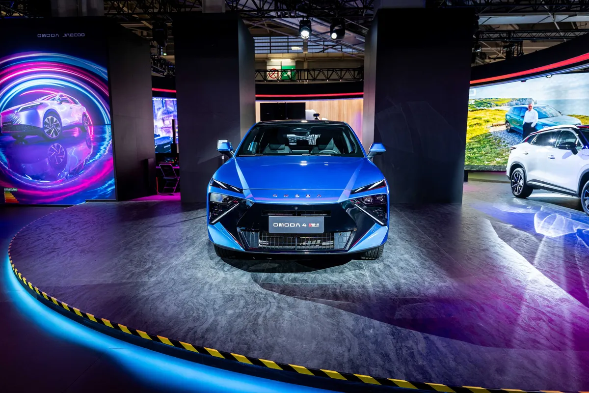Blauer Omoda 4 frontal auf einer runden, beleuchteten Bühne auf der Paris Motor Show.