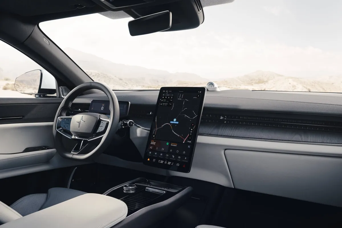 Cockpit des Polestar 3 mit Lenkrad, kleinem Fahrerdisplay, hochkant stehendem Bildschirm in der Mitte und hellen Sitzen.