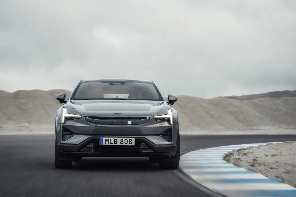 Grauer Polestar 3 fährt fast frontal durch eine Kurve mit blau-weißen Randmarkierungen.