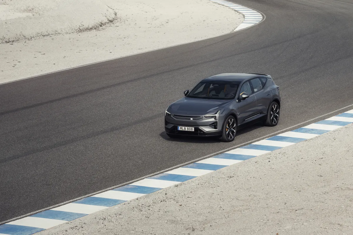 Dunkelgrauer Polestar 3 von oben in einer weiten Kurve mit blau-weißen Randmarkierungen.