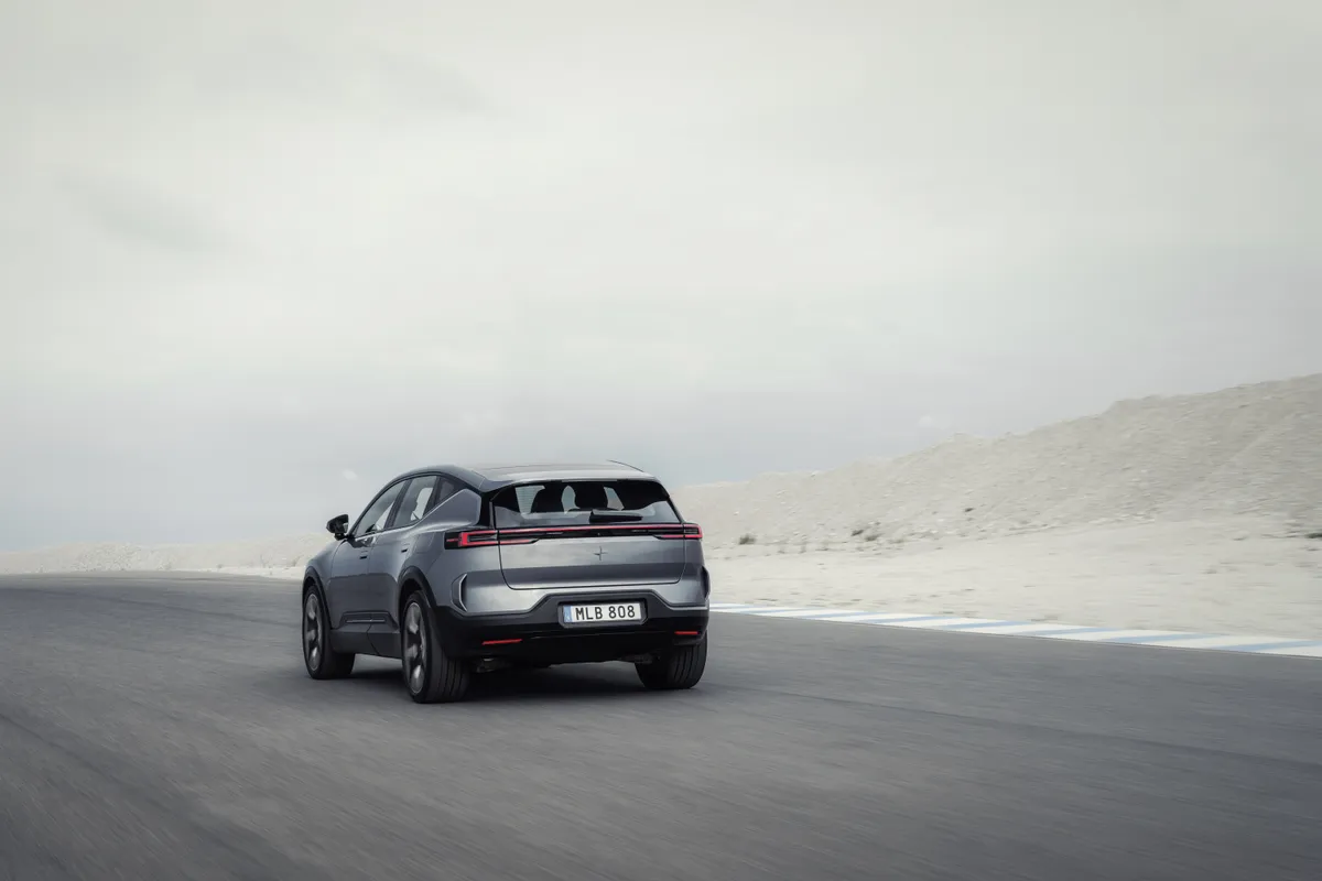 Grauer Polestar 3 von schräg hinten auf einer breiten Teststrecke in karger Landschaft.