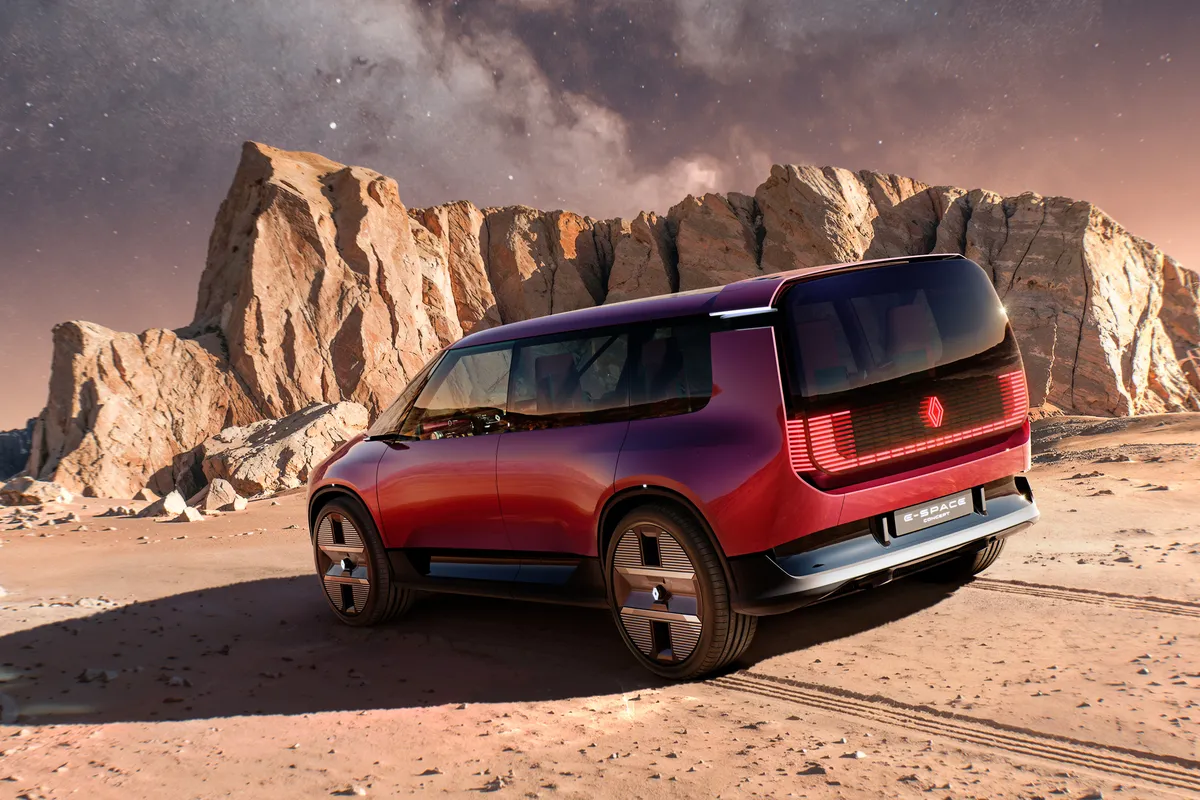 Rotes E-Space Concept von schräg hinten vor Felswänden, mit leuchtenden Rückleuchten.
