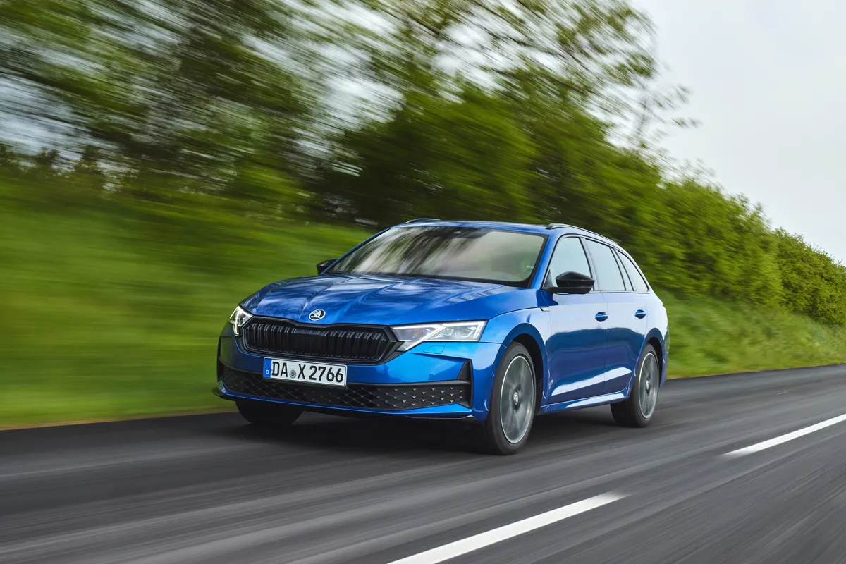 Blauer Škoda Octavia der vierten Generation nach dem Facelift fährt auf einer Allee, von schräg vorne fotografiert.