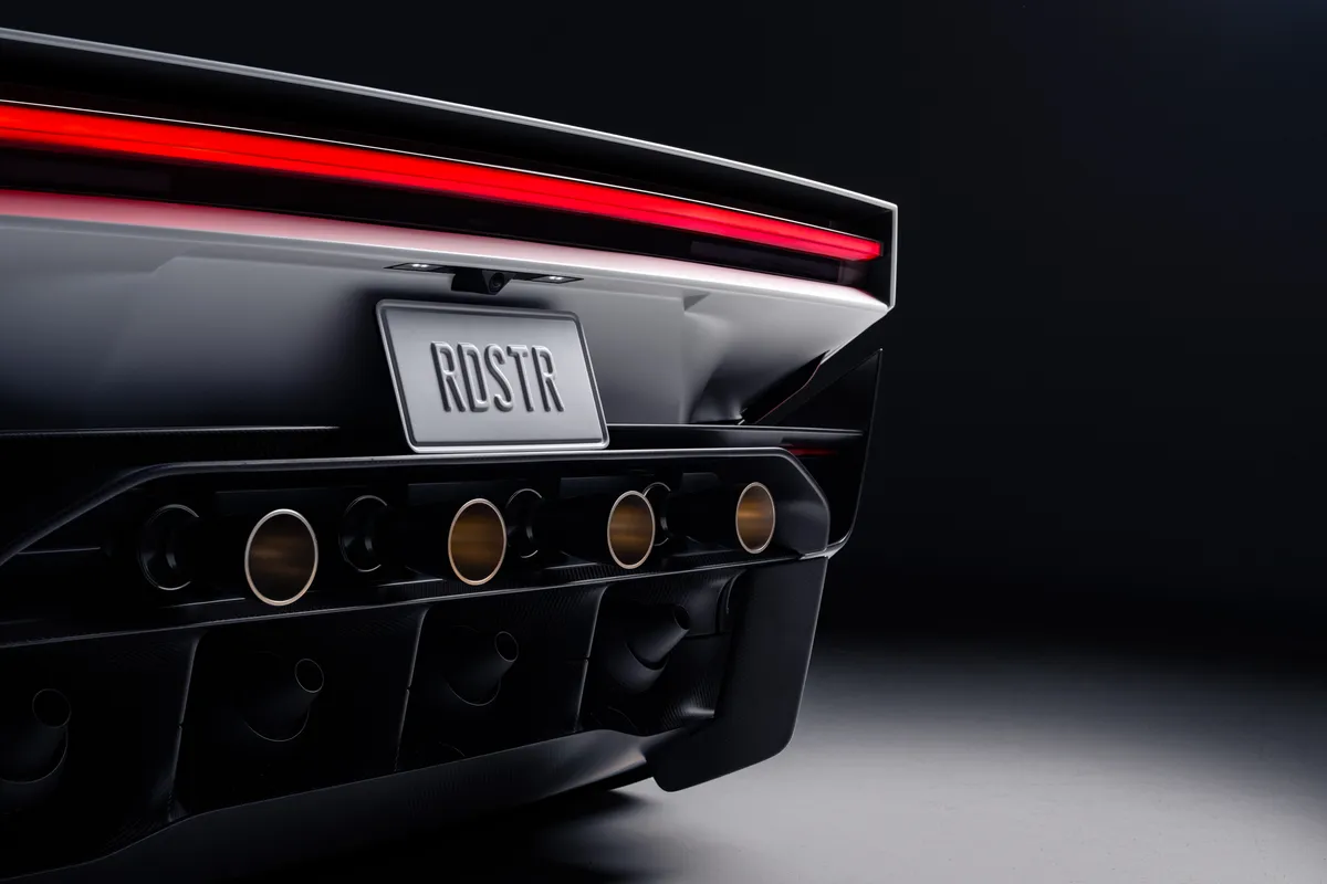 Nahaufnahme des Hecks des Tesla Roadster mit rotem Leuchtband, Kennzeichen „RDSTR“ und vier runden Düsenöffnungen.
