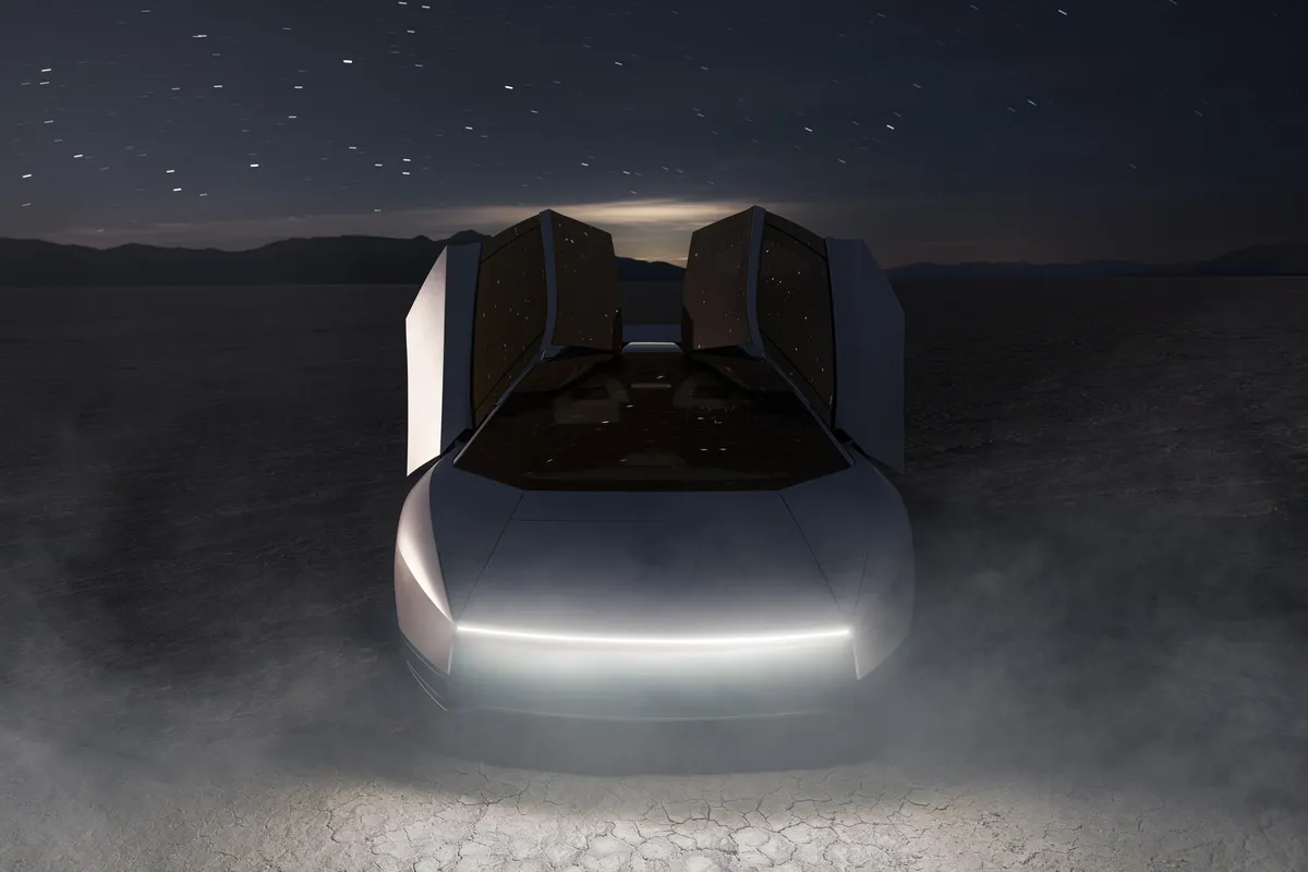 Silberner Tesla Roadster frontal mit beiden hochgeöffneten Türen und leuchtendem weißem Frontlichtband in einer nebligen Wüstenlandschaft unter Sternenhimmel.
