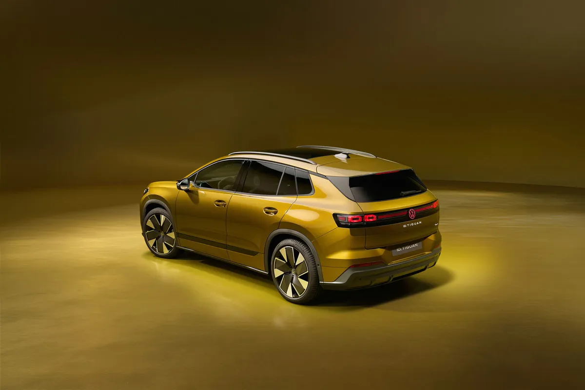 Der goldfarbene VW ID. Tiguan von schräg oben hinten mit leuchtendem Heckband.