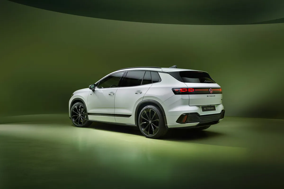 Weißer VW ID. Tiguan von hinten schräg links vor grünem Hintergrund.