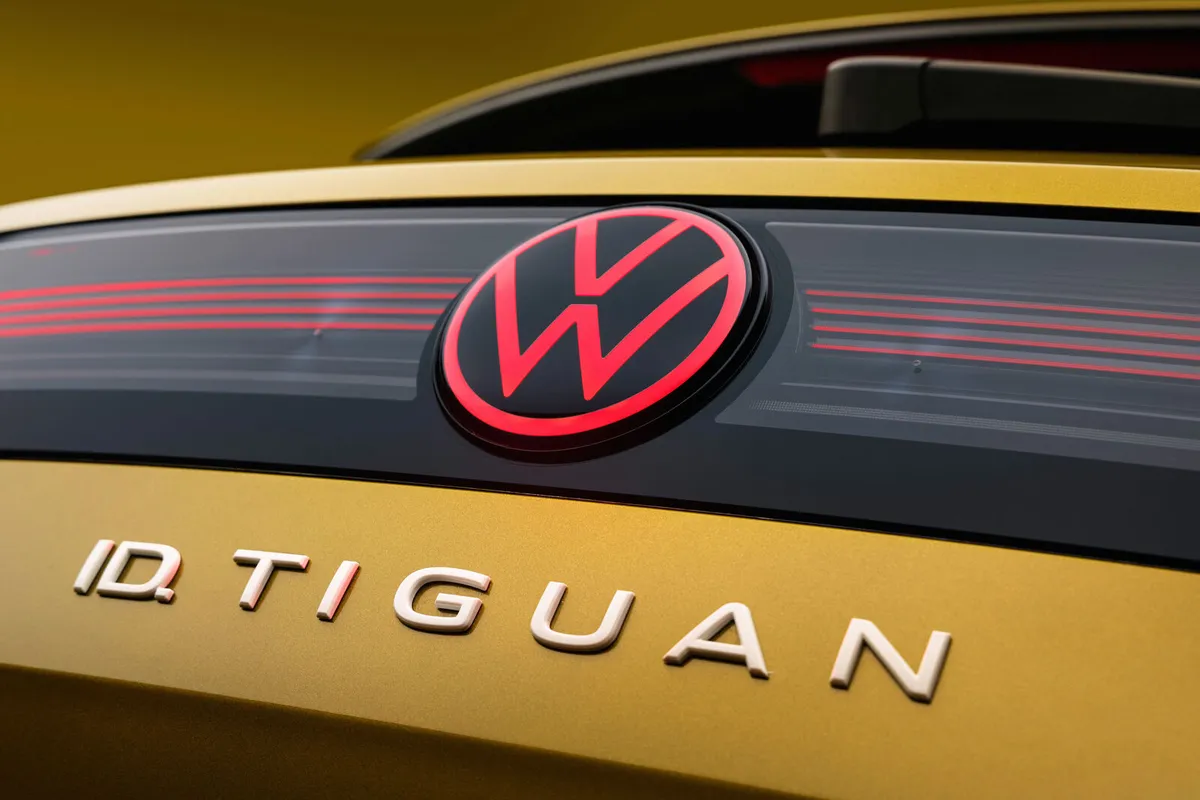 Nahaufnahme des Hecks mit rot beleuchtetem VW-Logo und Schriftzug ID. TIGUAN.