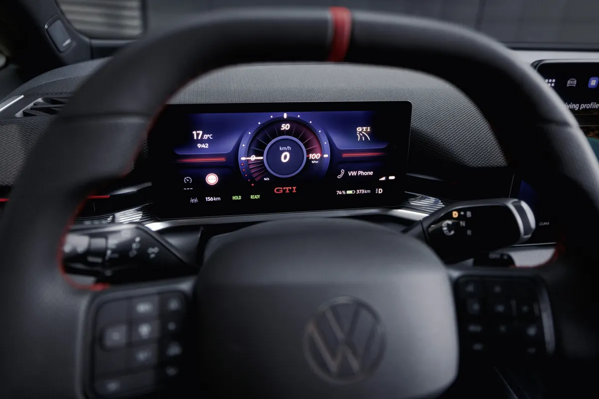 Schwarzes Multifunktionslenkrad des ID.3 GTI mit roter Zwölf-Uhr-Markierung vor dem digitalen Kombiinstrument mit GTI-Schriftzug.
