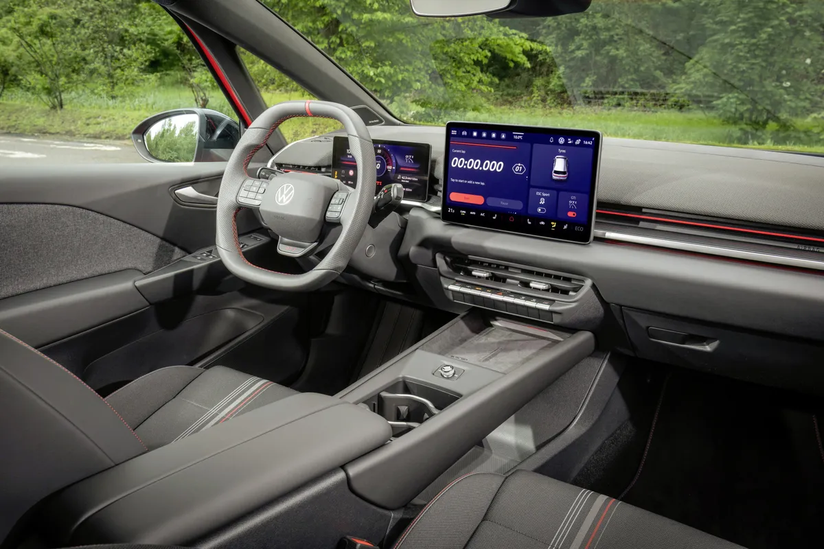 Grauschwarzes Cockpit des ID.3 GTI mit Multifunktionslenkrad, digitalem Kombiinstrument, zentralem Touchscreen und roten Zierlinien.