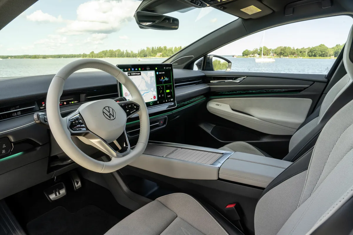 Innenraum des VW ID.7 mit hellen Sitzen, Lenkrad, großem Zentraldisplay und Mittelkonsole.